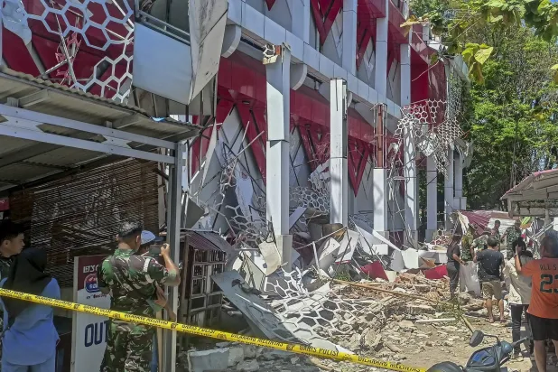 أشخاص يتفقدون مبنى تضرر جراء زلزال ضرب مانادو في شمال سولاويزي في إندونيسيا (إ.ب.أ)