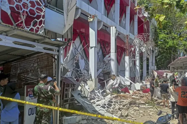 Endonezya'nın Kuzey Sulawesi bölgesindeki Manado'da meydana gelen depremde hasar gören bir binayı inceleyenler (EPA).