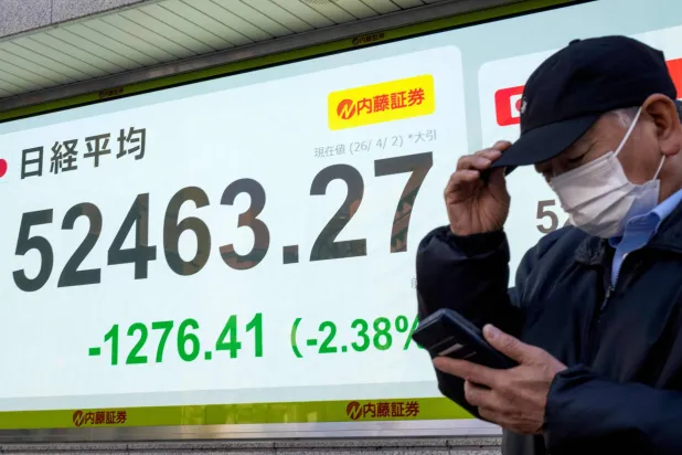 رجل يقف أمام شاشة تعرض حركة الأسهم في وسط العاصمة اليابانية طوكيو (أ.ف.ب)