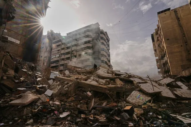 A man stands atop the rubble as smoke rises from a building destroyed in an Israeli airstrike in Dahieh, Beirut's southern suburbs, Lebanon, March 14, 2026. (AP)