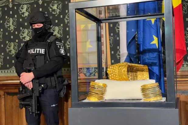 A police officer stands by a stolen artifact from Romania, the 2,500-year-old Cotofenesti helmet, recovered in Netherlands, is shown during a press conference in Assen, Netherlands, Thursday, April 2, 2026. (AP Photo/Aleksandar Furtula) 