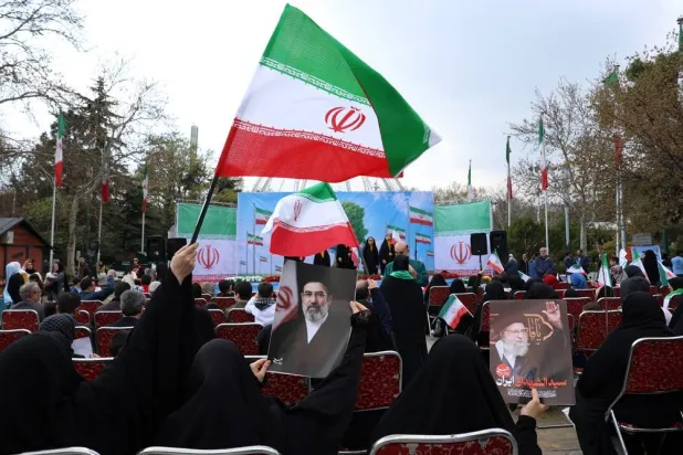 Iranian women clad in black chadors wave national flags and hold posters of Iranian Supreme Leader Mojtaba Khamenei (C) and of his late father, former Iranian Supreme Leader Ali Khamenei (R), during the annual Nature Day festival in Tehran, Iran, 02 April 2026. (EPA)