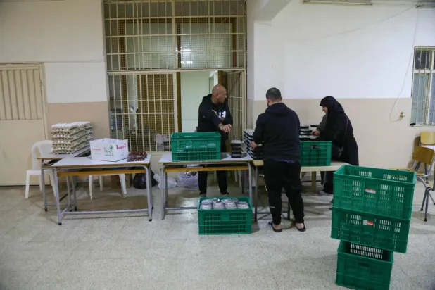 عاملون ومتطوعون في مبادرة لمنظمة غير حكومية يوزعون وجبات الطعام بمدرسة تؤوي نازحين في سن الفيل شرق بيروت 28 مارس 2026 (أ.ف.ب)