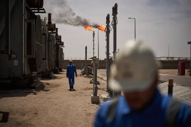 FILE - Workers walk in an area at a degassing station in Zubair oil field, whose operations have being reduced due to the Mideast war triggered by the US and Israeli attacks on Iran, near Basra, Iraq, March 28, 2026. (AP Photo/Leo Correa, File)