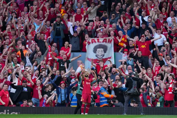 Liverpool's Mohamed Salah takes a selfie with a fans smartphone as he celebrates after scoring his side's fourth goal during the English Premier League soccer match between Liverpool and Tottenham Hotspur at Anfield in Liverpool, England, Sunday, April 27, 2025. (AP)