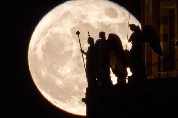 يرتفع القمر بدراً خلف تماثيل الملائكة في كاتدرائية القديس إسحاق في سانت بطرسبرغ، روسيا (أ.ب)