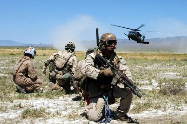 عناصر الإنقاذ المظلي التابعون لسلاح الجو الأميركي بالإضافة إلى شخص يُحاكي عملية «النجاة» يراقبون هبوط مروحية بوصف ذلك جزءاً من عملية تدريبية للجيش (أرشيفية - سلاح الجو الأميركي)