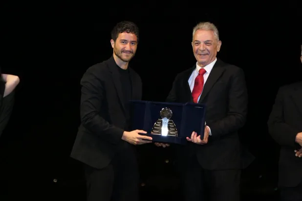 أحمد مالك متسلماً الجائزة من الرئيس الشرفي للمهرجان محمود حميدة (إدارة المهرجان)