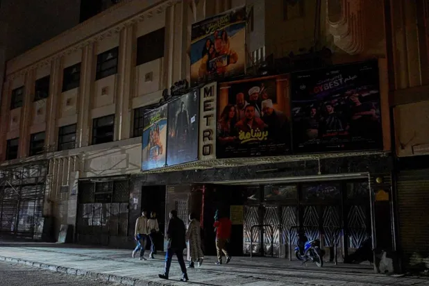 People walk past a closed cinema as shops close early under a government-ordered curfew aimed at reducing energy costs in downtown Cairo on April 2, 2026. (AFP)