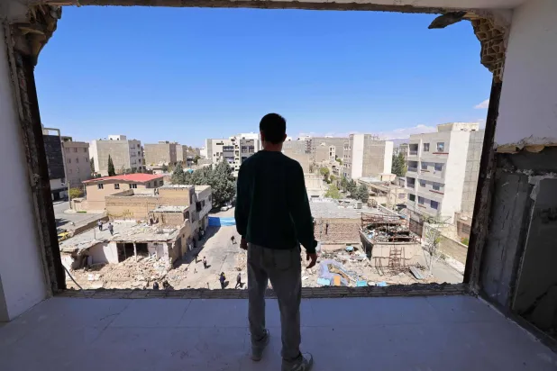 A man looks at the residential buildings that were damaged by recent strikes at Vahdat town in Karaj, southwest of Tehran on April 3, 2026. (AFP)