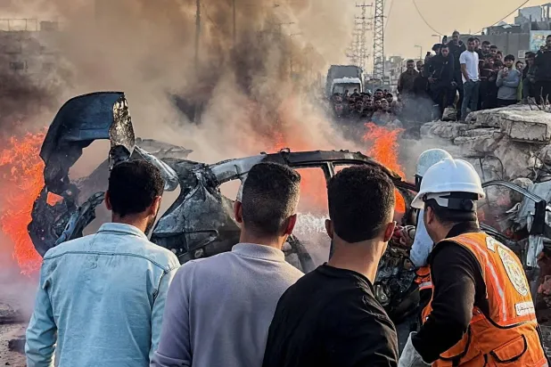 فلسطينيون يتفقدون موقعاً قال مسعفون إنه شهد غارة جوية إسرائيلية استهدفت سيارة قرب مدخل بلدة زويدا وسط غزة (رويترز)