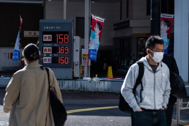 ركاب السيارات في طريقهم إلى العمل صباحاً أمام محطة وقود بطوكيو (أ.ف.ب)