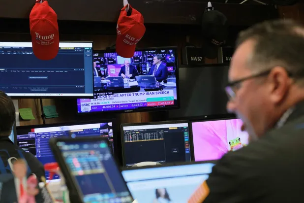 متداول يتابع الأخبار المالية على الشاشات في بورصة نيويورك (أ.ف.ب)