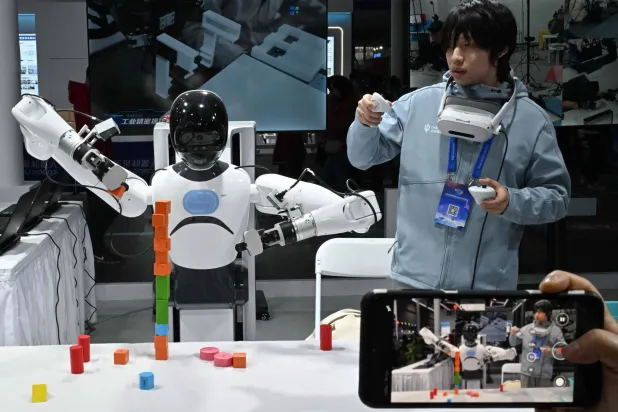 مهندس يتحكم في روبوت من شركة «تاشان» خلال مهرجان بكين (أ.ف.ب)