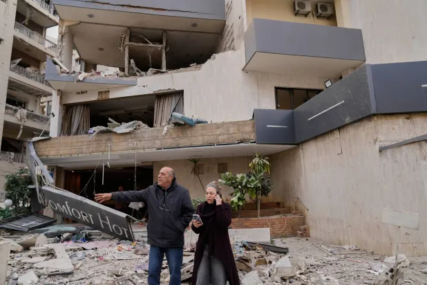 أشخاص يقفون أمام فندق متضرّر جرّاء غارة جوية إسرائيلية استهدفته في منطقة الحازمية شرق بيروت (أ.ب)