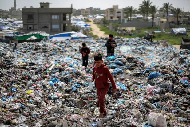 أطفال يبحثون عن مواد قابلة للتدوير في ساحة نفايات بمخيم البريج للاجئين الفلسطينيين بغزة (أ.ف.ب)