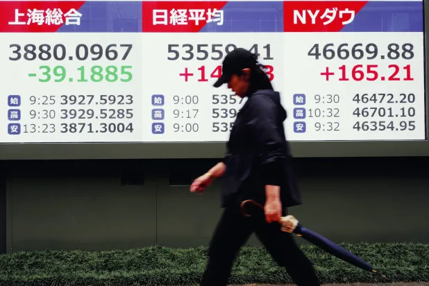 سيدة تمر أمام شاشة تعرض حركة الأسهم في وسط العاصمة اليابانية طوكيو (أ.ب)