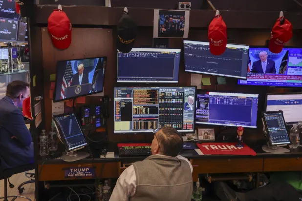 متداول في قاعة بورصة نيويورك بينما تُظهر الشاشة خطاب الرئيس دونالد ترمب خلال مؤتمر صحافي حول الحرب مع إيران (إ.ب.أ)