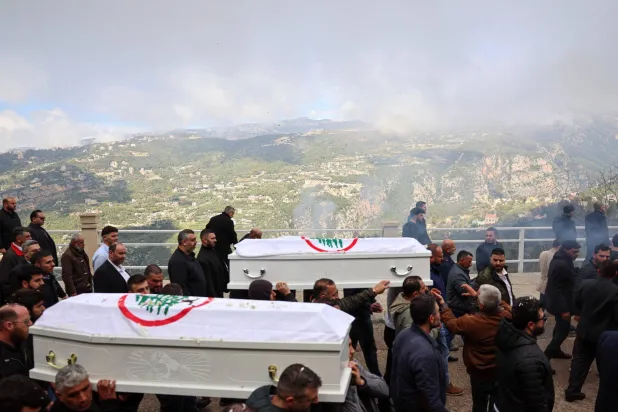 نعشا القيادي في «القوات اللبنانية» بيار معوض وزوجته فلافيا ملفوفتين بعلم «القوات» خلال تشييعهما بعد يومين على مقتلهما بغارة إسرائيلية استهدفت منطقة عين سعادة شرق بيروت (رويترز)