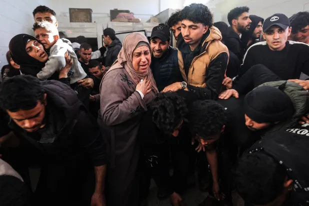 فلسطينيون يبكون خلال تشييع أحد أقاربهم من مستشفى «شهداء الأقصى» في دير البلح يوم الثلاثاء بعد مقتله في غارة إسرائيلية وسط غزة يوم الاثنين (أ.ف.ب)