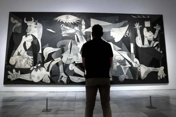 A visitor looks at Spanish painter Pablo Picasso's master piece "Guernica" during a press conference presenting the "Year of Picasso" events, marking the 50th anniversary of the painter's death, at the Reina Sofia museum in Madrid, on September 12, 2022. (Thomas Coex/ AFP)