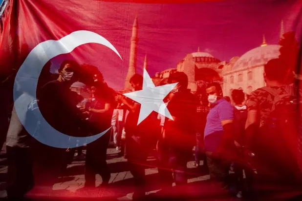 10 July 2020, Türkiye, Istanbul: People stand behind a Turkish national flag in front of Hagia Sophia in Istanbul. (dpa)