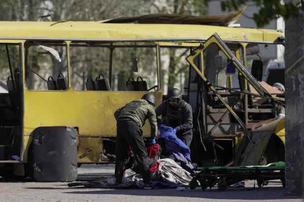 رجال إنقاذ يحملون جثة من الحافلة التي أصابتها مُسيّرة روسية بوسط ​مدينة ‌نيكوبول جنوب شرقي أوكرانيا الثلاثاء (رويترز)