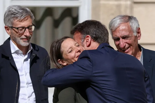 الرئيس الفرنسي إيمانويل ماكرون معانقاً سيسيل كوهلر في حديقة قصر الإليزيه بعد وصولها إلى باريس عقب 4 سنوات احتجاز بإيران (أ.ف.ب)