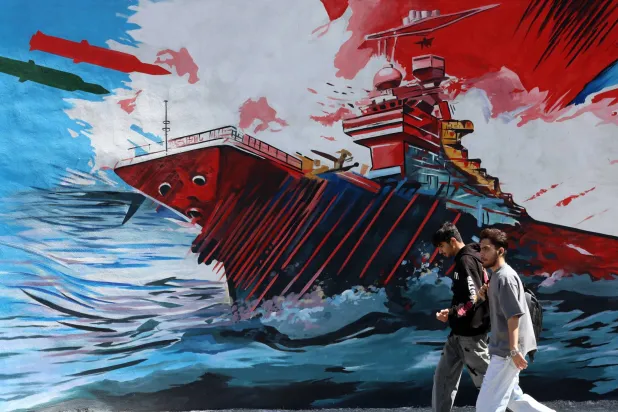 رجلان يمران أمام لوحة جدارية مناهضة للولايات المتحدة وإسرائيل في طهران (إ.ب.أ)