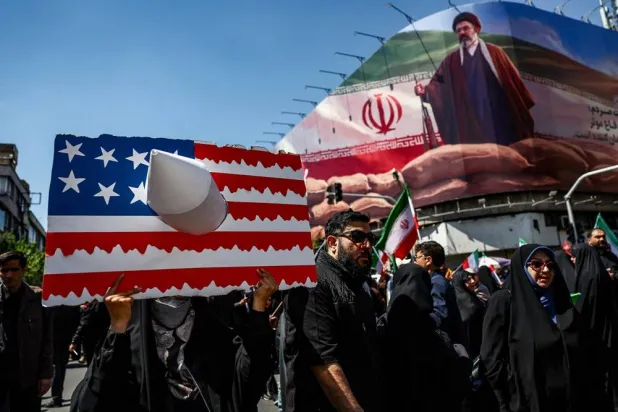A person holds a placard representing a US flag, with an image of Iran's new Supreme Leader Mojtaba Khamenei on a billboard in the background, on the day of a ceremony marking 40 days since Ali Khamenei was killed in Israeli and US strikes, in Tehran, Iran, April 9, 2026. Majid Asgaripour/WANA (West Asia News Agency) via Reuters 