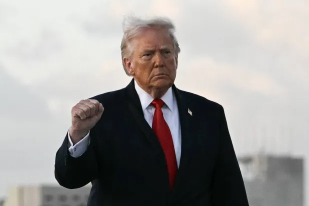US President Donald Trump makes a fist upon arrival at Miami International Airport in Miami, on April 11, 2026. Trump is traveling to Florida to attend a UFC event and spend the weekend at his Mar-a-Lago residence. (Photo by Jim WATSON / AFP)