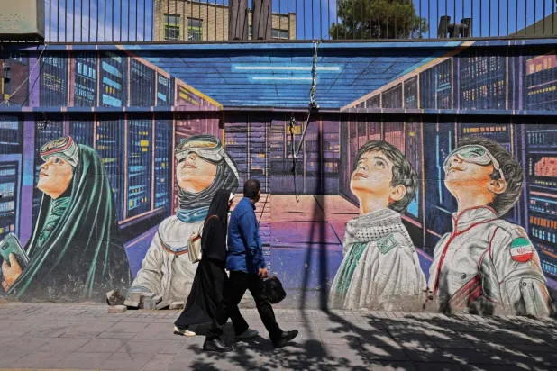 People walk past a wall mural along the roadside in Tehran on Sunday. AFP