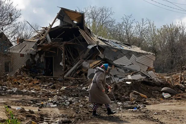 An elderly woman walks past the ruins of a house, which was destroyed during what Russian-installed authorities called a Ukrainian overnight drone attack, in the course of Russia-Ukraine conflict in Yasynuvata (Yasinovataya) in the Donetsk region, a Russian-controlled area of Ukraine, April 11, 2026. (Reuters)