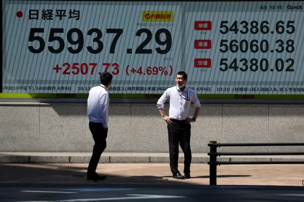 مشاة يمرُّون أمام شاشة تعرض حركة الأسهم في العاصمة اليابانية طوكيو (رويترز)