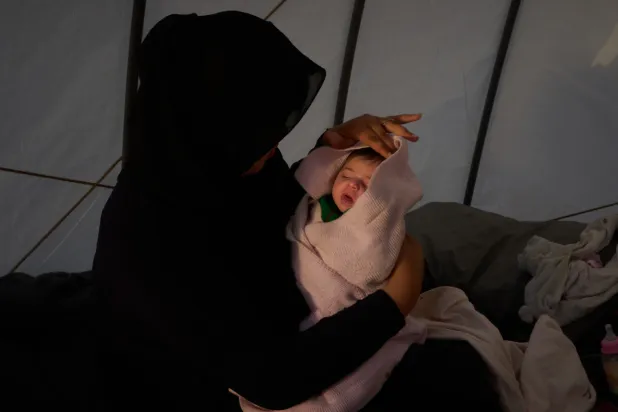 Haifa Kenjo, who fled Israeli airstrikes on the southern suburbs of Beirut, holds her 15-day-old daughter Shiman inside the tent she uses as a shelter and where she gave birth to her in Beirut, Sunday, April 12, 2026. (AP Photo/Emilio Morenatti)
