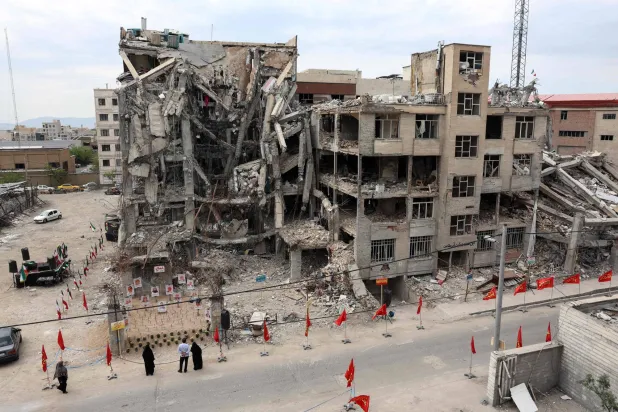 Iranians look at portraits of victims reportedly killed in a US-Israeli airstrike on the residential building near which they are displayed, in Tehran on April 13, 2026. (AFP)