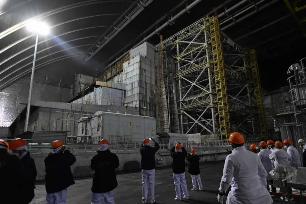Representatives of Greenpeace and media stand in front of the sarcophagus covering the destroyed fourth reactor under the New Safe Confinement (NSC), at the Chernobyl Nuclear Power Plant on April 9, 2026. (AFP)