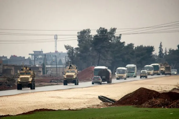 US military vehicles move along a road in a convoy transporting ISIS group detainees being transferred to Iraq from Syria, on the outskirts of Qahtaniyah in Syria's northeastern Hasakeh province on February 7, 2026. (AFP) 