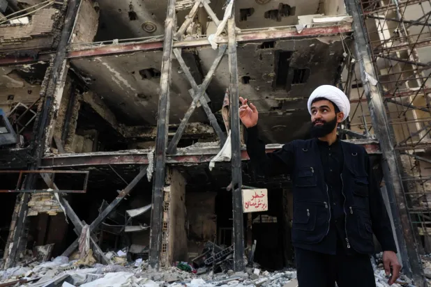 رجل دين إيراني يتحدث إلى وسائل الإعلام أمام مبنى سكني تعرض لغارات جوية أميركية - إسرائيلية قبل أيام من دخول وقف إطلاق النار لمدة أسبوعين بين إيران والولايات المتحدة حيز التنفيذ... اليوم في طهران (أ.ف.ب)