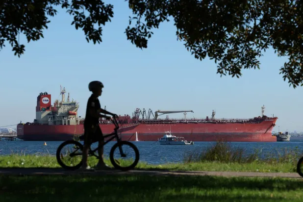 A cild pushes a bicycle near Grand Winner 1, an oil and chemical tanker, moored at Kurnell in Sydney, Australia, April 15, 2026. (Reuters)