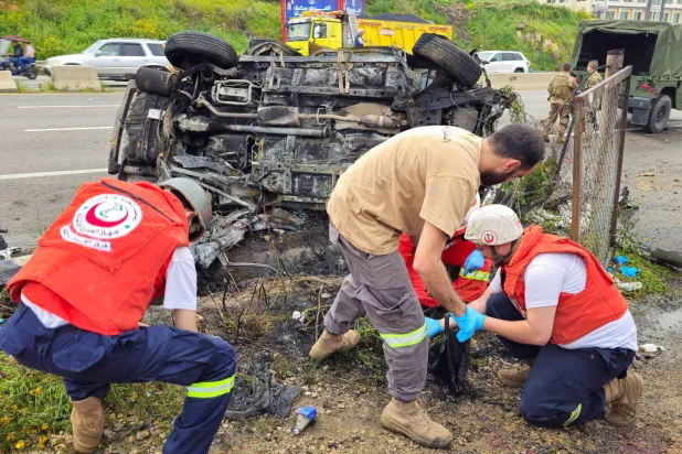 Lübnan Sivil Savunma Müdürlüğü ekipleri, es-Saadiyat’ta İsrail saldırısının hedef aldığı aracı inceliyor. (Reuters)
