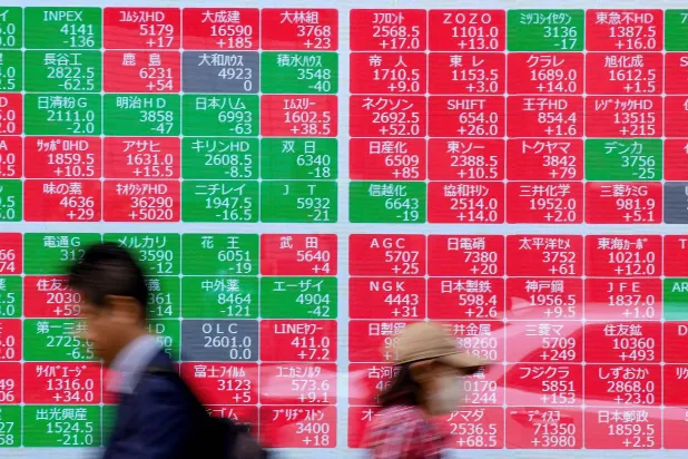 مشاة يمرون أمام شاشة تعرض حركة الأسهم في وسط العاصمة اليابانية طوكيو (أ.ف.ب)