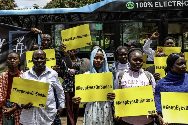Some of the Sudanese civilian refugees and human rights activists hold placards with the wordings, 'KeepEyesOnSudan' outside a bus branded during a commemorative gathering dubbed 'Under the Neema (Tree)' to mark the third anniversary since the war in Sudan started, organized by the Amnesty International at the Freedom Corner in Nairobi, Kenya, 15 April 2026. EPA/DANIEL IRUNGU