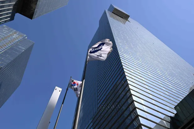 A South Korean national flag (L) and a Samsung flag (R) flutter outside the company's Seocho building in Seoul on April 7, 2026. (Photo by Jung Yeon-je / AFP)