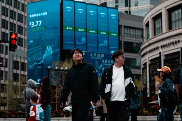 مشاة يمرون أمام شاشة تعرض حركة الأسهم في مدينة شنغهاي الصينية (إ.ب.أ)