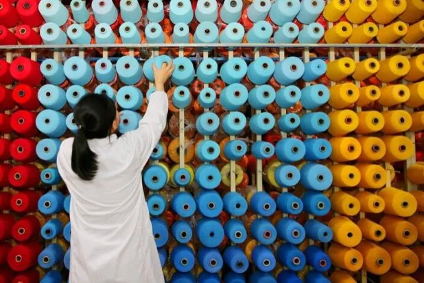 موظفة ترتّب بكرات الخيوط في مصنع نسيج في هايان بمقاطعة جيانغسو - الصين (رويترز)