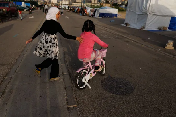 طفلتان نازحتان تلعبان بأحد مراكز النزوح في بيروت (رويترز)