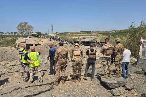 جنود الجيش اللبناني وعناصر الدفاع المدني يتفقدون موقع الغارات الإسرائيلية التي استهدفت جسر القاسمية المبني فوق نهر الليطاني في منطقة القاسمية جنوب لبنان (أ.ف.ب)