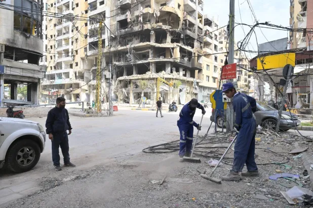 عمال ينظفون شوارع الضاحية الجنوبية لبيروت من الركام تمهيداً لعودة السكان (الشرق الأوسط)