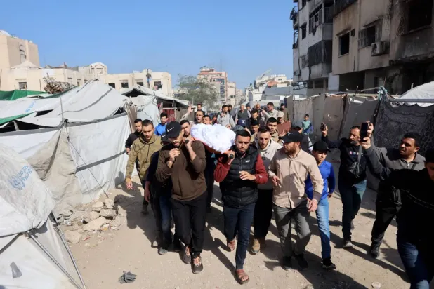 Filistinliler, İsrail'in Gazze şehrine düzenlediği baskında öldürülen bir kişinin cesedini taşıyor (AFP)